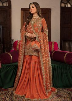 Outfit Type: Eastern Style: Gharara Package Includes: 4 Piece - Top Bottom Dupatta & Slip Fabric: Shirt: Raw Silk Slip: Raw Silk Gharara: Raw Silk Dupatta: Organza Color Type: Orange Best worn in: Winter Description: A burnt orange Korean raw silk short shirt is paired with a gharara and a heavily embellished gotta work dupatta to create a mesmerizing combination that radiates grace and luminosity. Due to its flawless fusion of contemporary design and classic craftsmanship, this attire is an exc Golden Sharara Pakistani, Heavy Sharara Designs For Wedding, Golden Sharara, Bridal Sharara, Gharara Designs, Sharara Designs, Pakistani Designer Clothes, Zardozi Work, Gotta Work