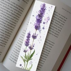 an open book with watercolor flowers on the cover and in front of it is a purple flower