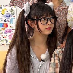 a girl with long hair and glasses standing next to another girl