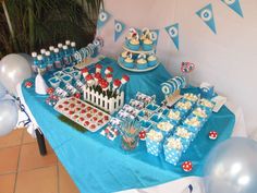 a blue table topped with cake and cupcakes