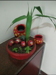 a potted plant sitting on top of a table next to two red vases