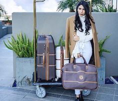 a woman is standing next to her luggage and holding the handlebars on a cart