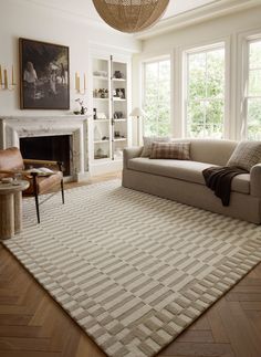 a living room filled with furniture and a large rug on the floor in front of a fire place