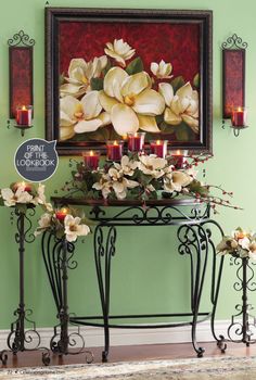 a table with flowers and candles on it in front of a framed art piece that says spring is coming