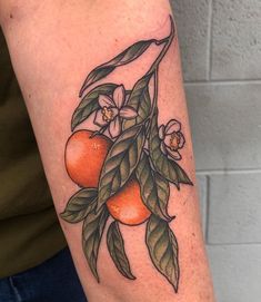 a close up of a person's arm with tattoos on it and oranges