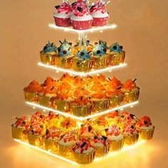 three tiered cupcake display with frosting and toppings on each tier, lit up by led lights