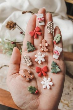 a person's hand is full of miniature christmas decorations, including gingerbreads and candy canes