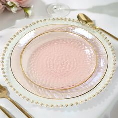 a pink and white plate with gold beading on the rim is sitting on a table