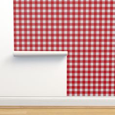 a red and white checkered wallpaper with a roll of paper in front of it