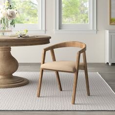 a wooden chair sitting next to a round table on top of a white area rug