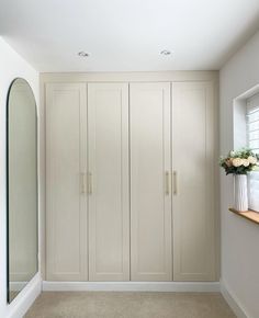 an empty room with white cupboards and flowers