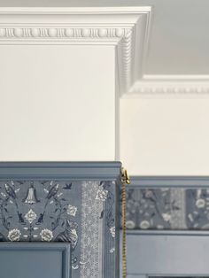 two blue cabinets with decorative wallpaper on the top and bottom, one has a gold chain hanging from it's side