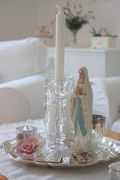 a table with a candle and figurine on it in front of a white couch