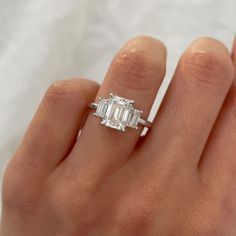 a woman's hand with a diamond ring on her left and an emerald stone in the middle