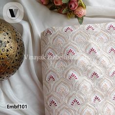 a vase with flowers on it next to a bed sheet and pillow cover that has an intricate design