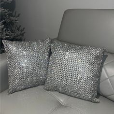 two silver sequin pillows sitting on top of a white couch next to a christmas tree