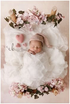 a newborn baby is sleeping in a white blanket surrounded by pink flowers