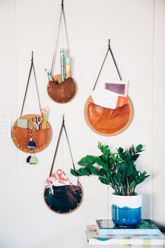 three hanging wooden circles on the wall with plants in front of them and bookshelves