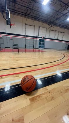 a basketball sitting on the floor in an empty gym