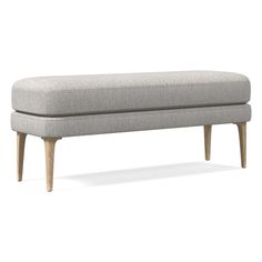 an upholstered bench with wooden legs and a gray fabric seat cover on it