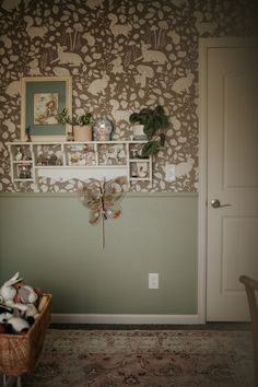 a room with a wall paper and shelves on the wall next to a basket filled with stuffed animals