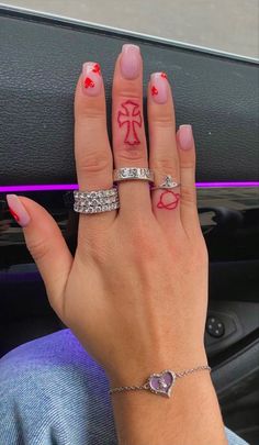 a woman's hand with three different rings on her fingers and one has a cross in the middle