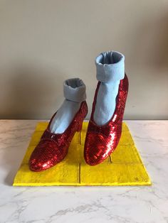 a pair of red sequinized shoes sitting on top of a yellow square mat