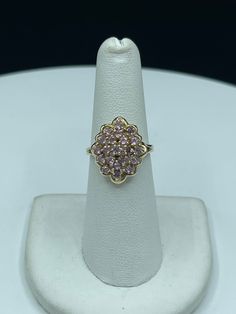 "This is a beautiful pink cubic zirconia 14k yellow gold cluster ring that is size 6.25. There are a total of 21 pink CZ stones all clustered together, and they sparkle like pink diamonds. The deck of this ring measures approximately 18 MM. This ring is also stamped 14k and \"Mexico\" as it was handmade in Mexico. This ring would be a great gift for that special someone. This ring is handmade, new, and unworn." Pink Gold Cubic Zirconia Ring, Luxury Pink Cluster Rings, Pink Cluster Ring For Gift - Fine Jewelry, Gold Flower-shaped Cluster Earrings With Cubic Zirconia, White Gold Hoop Earrings, Pink Cubic Zirconia Crystal Ring, Fine Jewelry, White Gold Hoops, Pink Diamond, Cluster Ring