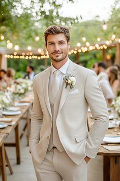 a man wearing a suit and tie standing in front of a table with white flowers