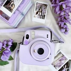 a purple camera sitting on top of a table next to flowers and pictures with polaroid frames