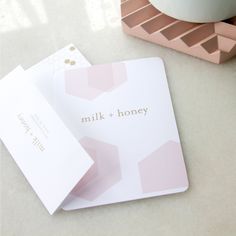 two pink and white cards sitting on top of a table next to a coffee cup