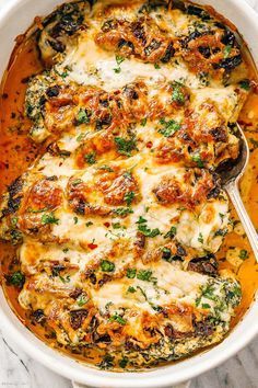 a casserole dish with cheese and spinach in it, on a marble surface