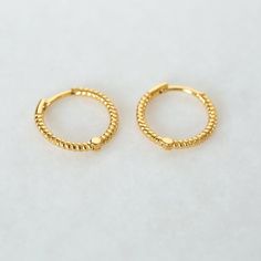 "A gorgeous classic - these little braided hoop earrings are understated and lightweight. Perfect for mixing and matching with other delicate earrings. * D E T A I L S * ∙ Sold individually (1 earring) or in pairs (2 earrings) ∙ Material: .925 Sterling Silver or 18K Gold Plated over .925 Sterling Silver ∙ Inner diameter: 10mm ∙ Hypoallergenic & nickel-free * P A C K A G I N G * ∙ All jewelry is sent out beautifully packaged in our signature box & ready for gifting. ∙ In order to reduce waste, we Trendy 14k Gold Filled Huggie Earrings, Trendy Hypoallergenic Yellow Gold Cartilage Earrings, Trendy Small Hoop Yellow Gold Earrings, Dainty Gold Plated Nickel Free Huggie Earrings, Adjustable Dainty Huggie Earrings, Trendy Adjustable Yellow Gold Earrings, Adjustable Hypoallergenic Huggie Earrings, Trendy Yellow Gold Hoop Earrings For Anniversary, Yellow Gold Small Hoop Cartilage Earrings