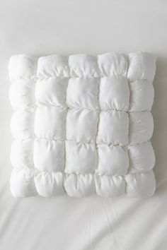 a white pillow that has been made out of some kind of material on top of a bed