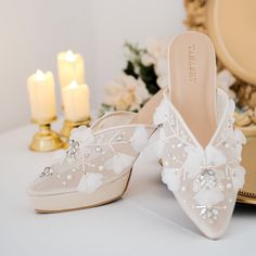 a pair of white shoes sitting on top of a table next to candles and flowers