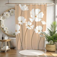 a shower curtain with white flowers on it in a bathroom next to a round mirror