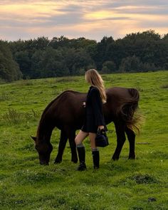 a woman standing next to a brown horse on top of a lush green field