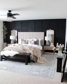 a bedroom with black walls and white carpeted flooring is decorated in neutral tones