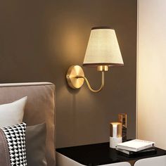 a lamp that is on the wall next to a table with pillows and a remote control