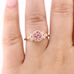 a woman's hand with a pink diamond ring on it