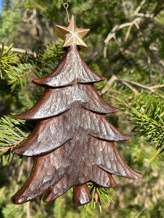 a wooden christmas tree ornament hanging from a pine tree with a star on top