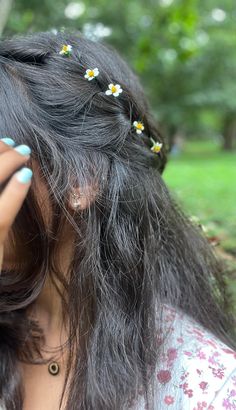 a woman holding her hair in the wind with daisies pinned to her long gray hair