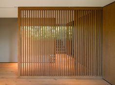 an open room with wooden slats on the wall and wood flooring in front of it