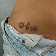 a woman's stomach with two seashells tattoo on her left side ribcage