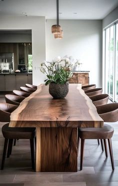 a large wooden table with chairs around it and flowers in a vase on the top