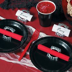 there are two black plates with red forks on them