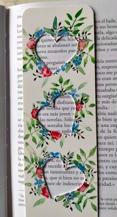 a bookmark with flowers and hearts on it in the middle of an open book