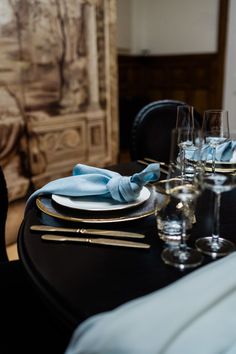 a table set with place settings and napkins on it, along with wine glasses