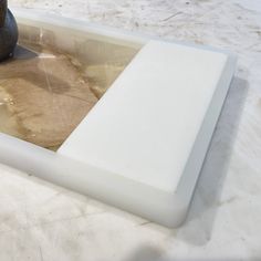 a vase sitting on top of a white table next to a brown and black object