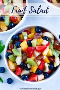 two bowls filled with fruit salad on top of a white counter next to mint leaves